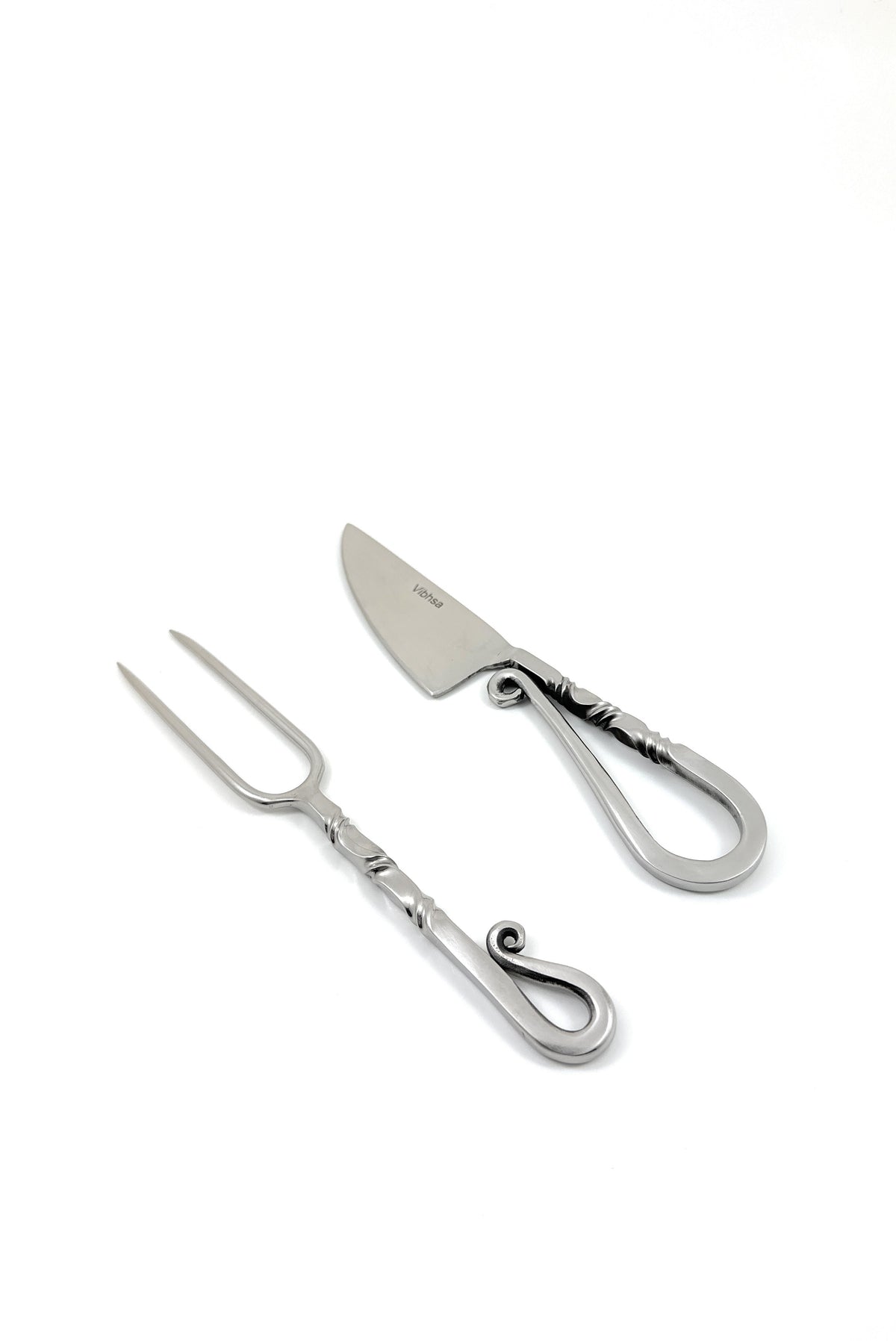 Stainless steel carving knife and two-prong fork with curled handles and decorative twisted details on a white background.