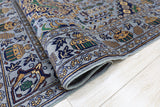 Close-up of a hand-knotted Afghani Zerkhaki wool rug with intricate geometric patterns in blue, green, gold, and white on a light wood floor.