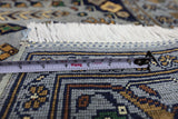 Close-up of a hand-knotted Afghani Zerkhaki wool rug showing detailed geometric patterns in blue, gold, and green with white fringe and a measuring tape across the rug.