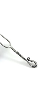 Close-up of a stainless steel carving fork featuring a twisted handle design ending in a curled loop, set against a white background.