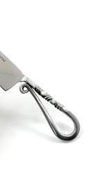 Close-up of a stainless steel carving knife handle with a distinctive twisted design and elegant curled end, highlighting its artisanal craftsmanship.