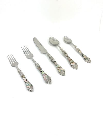 Stainless steel flatware pieces with seashell and wave patterned handles laid out on a surface