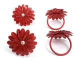 Set of four red floral napkin rings with layered petal design and a central white pearl, shown from top and side angles on a white background.