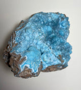 Botryoidal blue hemimorphite specimen with rounded bubbly formations and rough brown matrix on a white background.