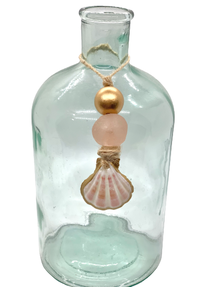 Clear glass bottle decorated with a twine necklace featuring a gold bead, a blush pink frosted bead, and a small pink scallop shell pendant.