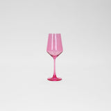 Single transparent bubblegum pink wine glass with a slender stem and faceted bowl, photographed against a plain white background.