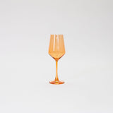 Single orange-tinted wine glass with a faceted bowl and slender stem, set against a plain white background.