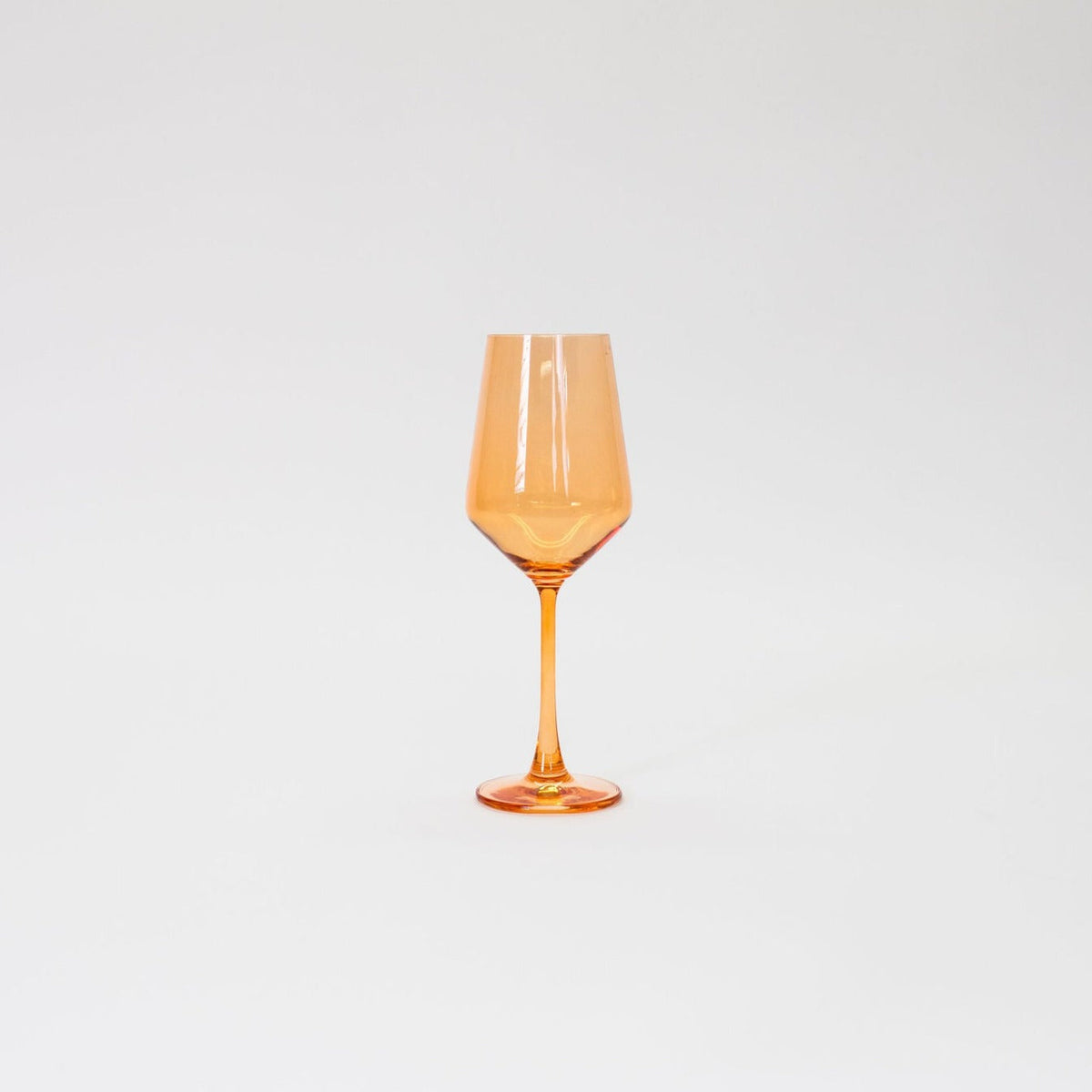 Single orange-tinted wine glass with a faceted bowl and slender stem, set against a plain white background.