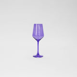 Tall wine glass made of translucent purple glass with a slender stem and a faceted bowl shape, shown against a plain light background.