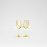Two lemon-yellow tinted wine glasses with hexagonal bowl shapes and slender stems, shown side by side on a white background.
