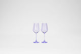 Two stemless lavender-colored wine glasses with a faceted bowl design, standing side by side on a white background.