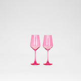 Two translucent bubblegum pink wine glasses with faceted bowls and slender stems, standing side by side on a white background.