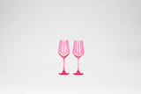 Two bubblegum pink stemless wine glasses with faceted sides, standing side by side on a plain white background.
