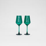 Two emerald green colored wine glasses with faceted bowl design and slender stems, standing side by side on a white surface against a plain background.