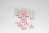 Set of six translucent pink wine glasses with long stems and slightly tapered bowls, arranged in a loose cluster on a white background.