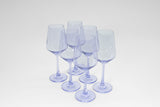 Six translucent lavender-colored stemmed wine glasses arranged in two rows on a white surface, showing their elegant shape and soft purple tint.