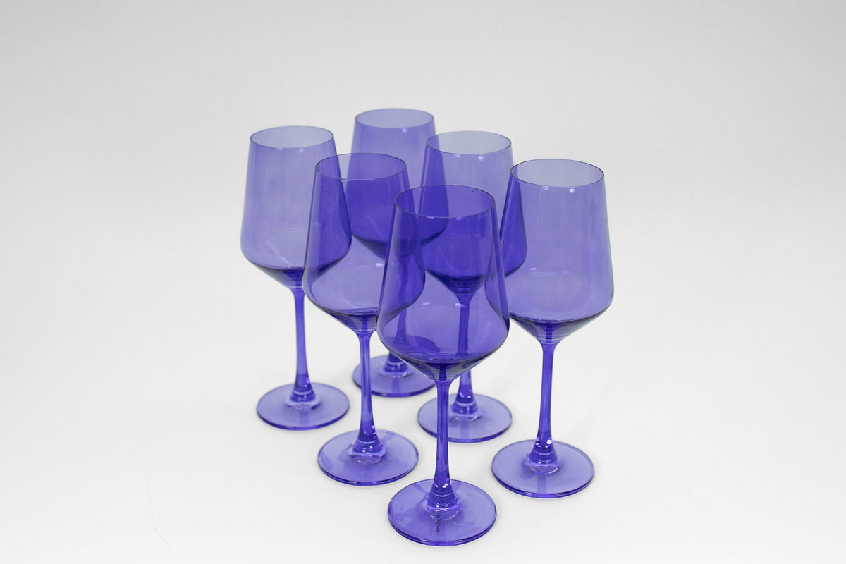 Set of six translucent purple wine glasses with rounded bowls and slender stems arranged in two rows on a plain white surface.