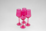Four translucent hot pink stemmed wine glasses grouped together on a light gray background, showing their elegant elongated bowl shape and slender stems.