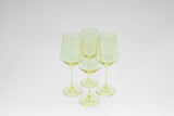 Four translucent lemon-drop yellow stemless wine glasses grouped on a white surface with subtle reflections.