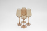 Four translucent brown stemmed wine glasses grouped closely on a white surface, showing subtle variations in shape between two glass styles.
