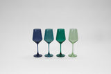Set of four stemmed wine glasses in varying translucent shades of blue, teal, dark green, and light green, arranged in a row on a white background.
