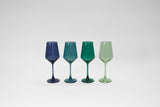 Four stemless colored wine glasses in blue and green shades set on a light surface