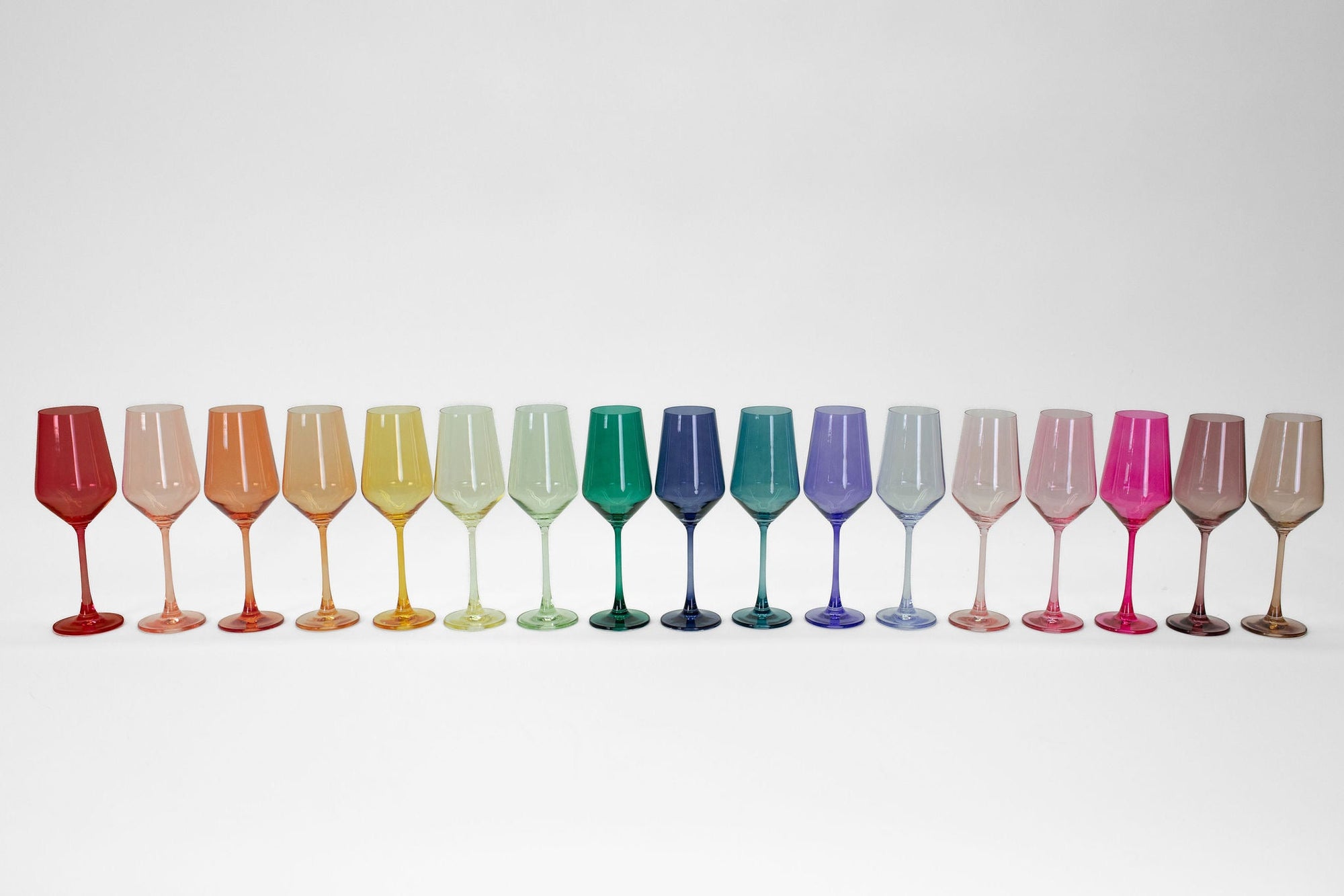 Set of 16 colored wine glasses arranged on a wooden table