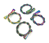Set of four twisted metal napkin rings with a rainbow iridescent finish, each featuring a looped design and tapered ends, arranged on a white background.