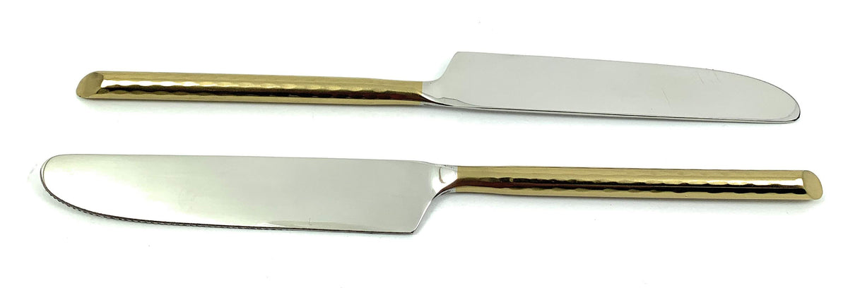 Set of six Vibhsa golden dinner knives arranged on a dark table surface