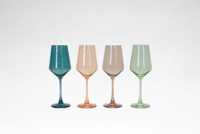 Four colored stemmed wine glasses in brown, peach, teal, and green hues from glasshauseco displayed on a table