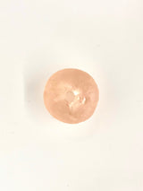 Translucent pale peach-colored round resin ornament with a subtle scallop shell texture, viewed from above on a plain white background.