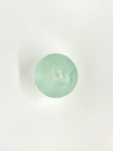 Round translucent pale green resin ornament with subtle sculpted details resembling a scallop shell on a white background