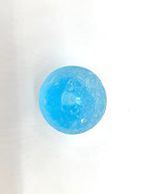 Close-up of a spherical blue resin piece with subtle texture and embedded bubbles, shown against a plain white background.