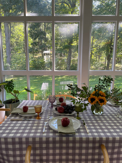 Lavender Gingham Tablecloth laid over a dining table with a dining setting