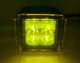 Square LED light pod emitting bright yellow-green light through a textured lens with four visible LEDs inside a black housing.