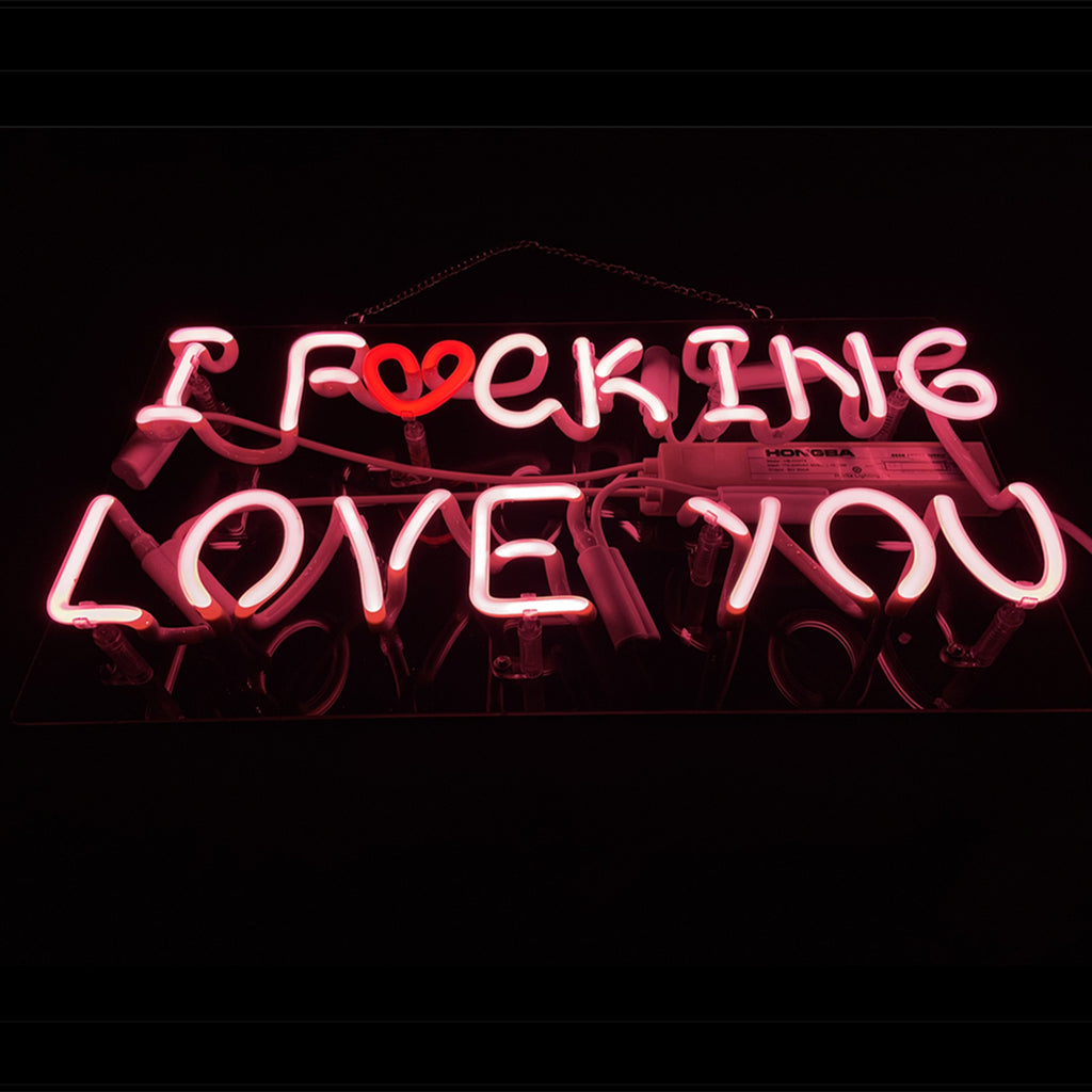 Pink neon sign reading 'I F♥CKING LOVE YOU' with a red heart replacing the 'U' in 'FUCKING', on a black background.