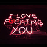 Pink neon sign displaying the phrase 'I LOVE FUCKING YOU' with a red heart shape replacing the letter 'U' in 'FUCKING' on a dark background.