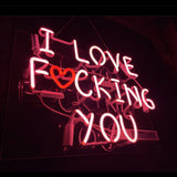 Pink neon sign spelling 'I LOVE FUCKING YOU' with a red heart symbol doubling as the letter O in 'FUCKING', glowing against a dark background.