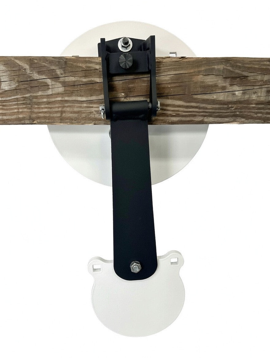 White circular metal shooting target with a smaller swinging target attached below, mounted on a horizontal weathered wooden beam with black metal bracket hardware.