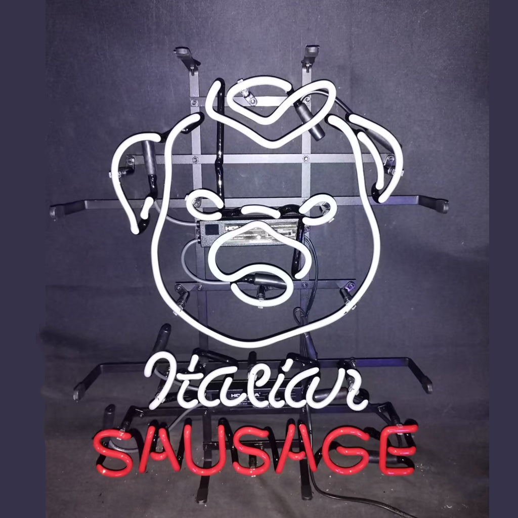 White neon outline of a smiling pig face with red neon text 'SAUSAGE' below and cursive white text 'Italian' above on a black background with metal mounting frame.