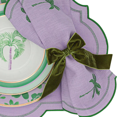 Set of four Jeweled Mirage Napkins in lilac linen with emerald green embroidered edging and palm tree motifs