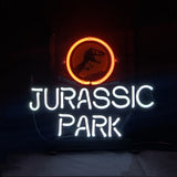 Neon sign with a red circle enclosing a black T-Rex silhouette above white glowing text spelling 'JURASSIC PARK' against a dark background.