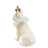 White dog figurine sitting with a red and gold crown on its head and a ruffled collar around its neck, shown from rear side.
