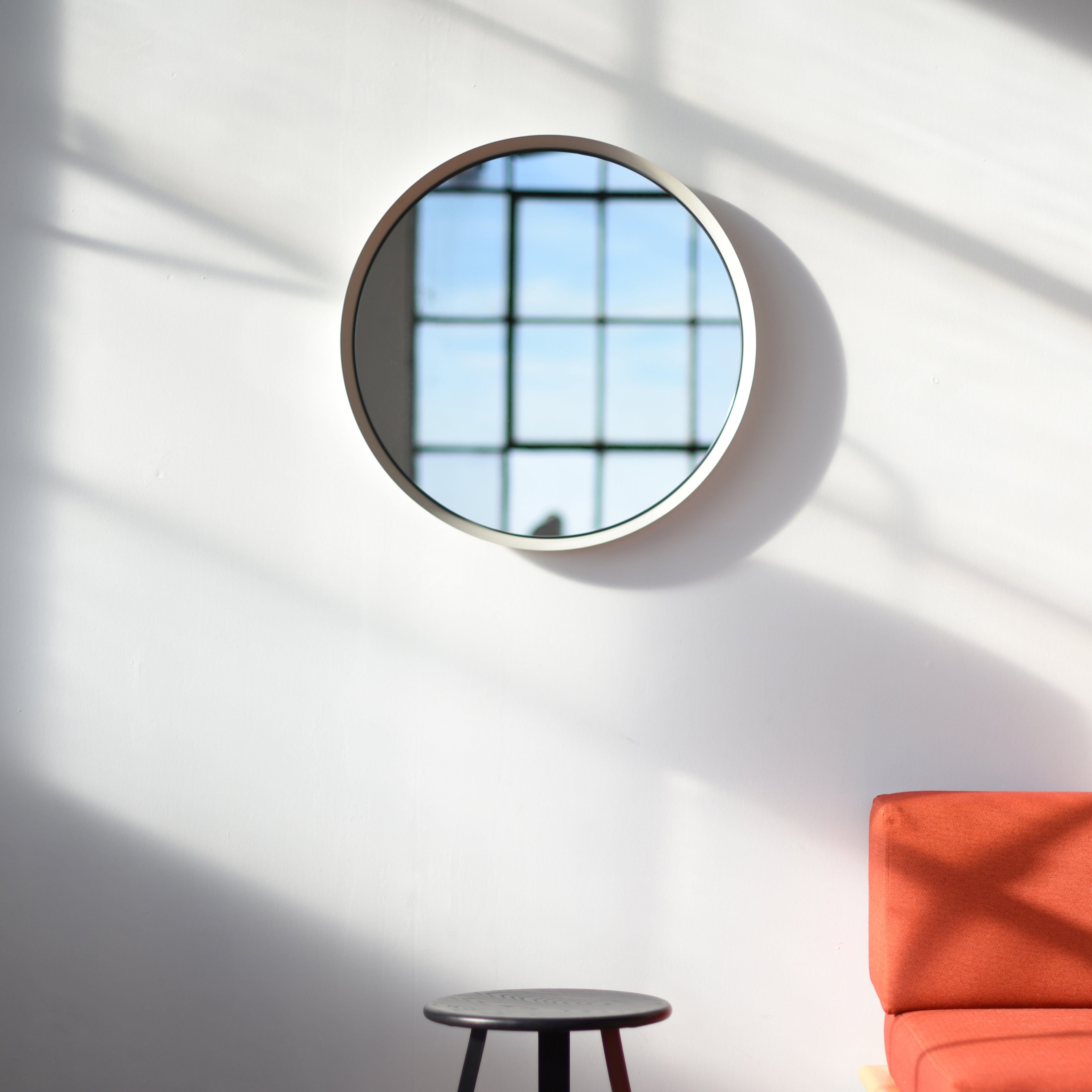 Kendrick Mirror with white spun steel frame hanging in a living space