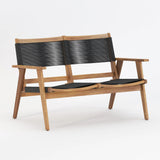 Two-seater wooden bench with light brown frame and black woven horizontal backrest and seat straps, angled legs, and simple armrests, shown at three-quarter view.