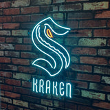 Bright blue neon sign in the shape of an 'S' with an orange eye detail, above glowing blue text spelling 'KRAKEN', mounted on a red brick wall.