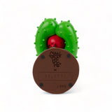 Bottom view of a decorative figurine with a brown round base labeled 'Seletti' and a green spiked cactus shape partially covering a red object above it.