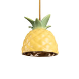 Ceiling lamp shaped like a yellow pineapple with textured rind and green leaves on top, suspended by a textured golden cord against a white background.
