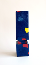 Tall, narrow vase with deep blue base color, featuring scattered red, yellow, and light blue abstract spots, composed of two stacked rectangular sections.