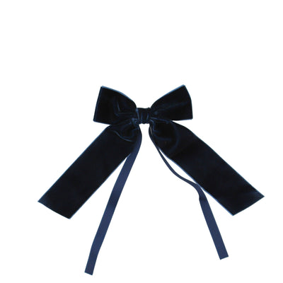 Set of six blue velvet napkin bow ties with attached blue ribbons arranged on a dark surface.